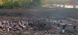Blasted ledge for removal and preparation for additional blasting along the east side of Briggs Street just south of Flynn Avenue. Protective blasting mats pictured in the background.